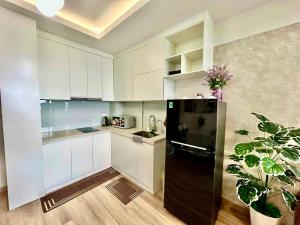 a kitchen with white cabinets and a black refrigerator at Jade's House Sapa - Stunning Views, 3BR, Kitchen & Washer, 5 Min to Town in Lao Cai