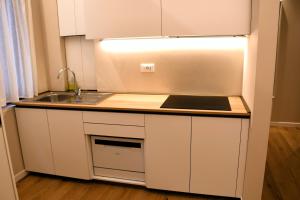 a white kitchen with a sink and a refrigerator at Alpine Escape 1BR Apartment A in Tarvisio +26 photos
