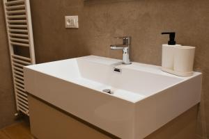 a bathroom with a white sink with a soap dispenser at Alpine Escape 1BR Apartment A in Tarvisio