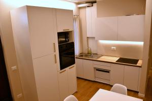 a kitchen with white cabinets and a stove top oven at Alpine Escape 1BR Apartment A in Tarvisio