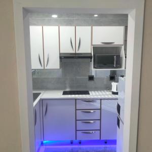 a kitchen with white cabinets and a blue light at Exclusive guest house in Modimolle