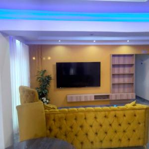 a living room with a yellow couch and a television at Exclusive guest house in Modimolle