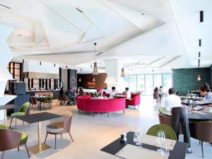 a restaurant with people sitting at tables and chairs at Novotel Convention And Spa in Antananarivo