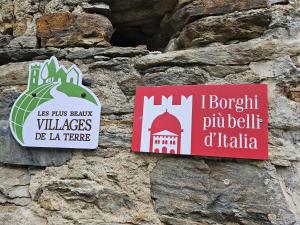 two signs on the side of a stone wall at Sotto il Cielo, Balcone panoramico sul borgo di Ingria in Ingria