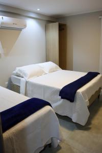 a bedroom with two beds with white and blue sheets at Catamarã Pé na Areia in Angra dos Reis