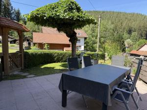 a table and chairs on a patio with a tree at Schwarzwaldhaus Zwink Ferienhaus in Enzklösterle