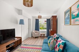 a living room with a blue couch and a tv at Willow Cottage, North Street in St. Andrews