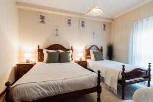 a bedroom with two beds and two lamps and a window at Vistas da Villa in Cabeceiras de Basto
