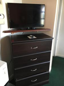 a dresser with a flat screen tv on top of it at Nassau Holiday Motel in Yulee