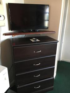 Una cómoda con un televisor de pantalla plana encima. en Nassau Holiday Motel, en Yulee