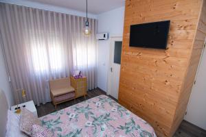 a bedroom with a wooden wall with a flat screen tv at Guest House D'Avenida in Vila Praia de Âncora
