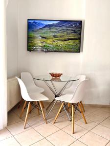 a dining room with a glass table and white chairs at SUNNY 2, Two-bedroom house with parking in Komotini