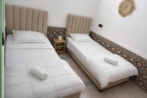 two beds in a room with white sheets and pillows at Palm Hostel in Marrakesh