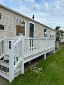 a mobile home with a white railing and a porch at The Pointon-Bordeaux Caravan Co in Rhyl