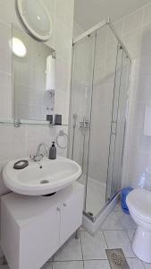 a white bathroom with a shower and a sink at Apartment Murva in Primošten