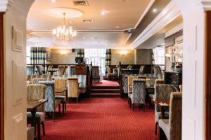 a dining room with tables and chairs and a chandelier at Adair Arms Hotel in Ballymena