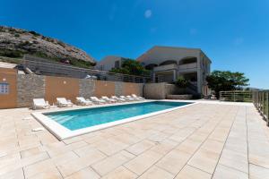 a swimming pool with chairs and a house at Apartments PoolHouse in Metajna