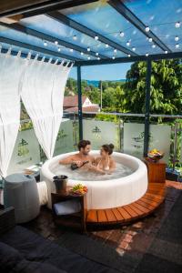 Ein Mann und eine Frau in einem Whirlpool auf einer Terrasse in der Unterkunft Hotel Tommy Wellness & Spa in Náchod