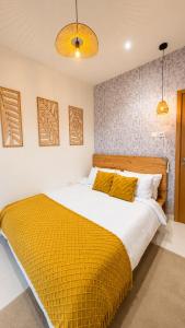 a bedroom with a large bed with a yellow blanket at The Luxe Cottage in Ikeja