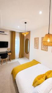 a bedroom with a large white bed with yellow sheets at The Luxe Cottage in Ikeja