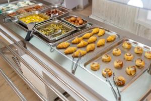 a buffet line with trays of pastries and other food at California Beach Hotel - Adults Only in Laganas
