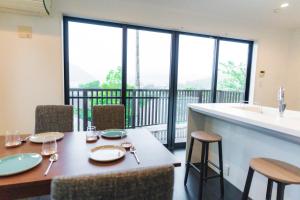 a dining room with a table with chairs and a balcony at SANMI Hayama in Hayama