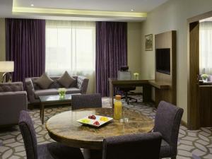 a hotel room with a table and a living room at Movenpick Hotel Qassim in Buraydah