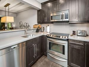 a kitchen with stainless steel appliances and wooden cabinets at Ptarmigan Townhome 2 in Vail