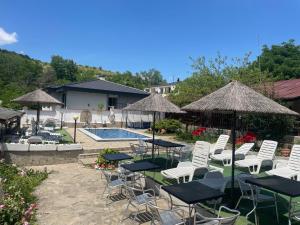 a group of chairs and tables with umbrellas and a pool at Семеен Хотел Сандим in Kŭrdzhali +20 photos