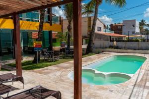 a swimming pool with a patio and a building at Pousada La Bella Luna in Porto De Galinhas