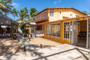 a yellow building with white doors and palm trees at Pousada La Bella Luna in Porto De Galinhas