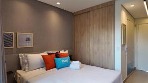 a bedroom with a white bed with colorful pillows at Ip Alto do Ipiranga by Xtay - Estúdio novo com cozinha e a 1 quadra da estação Alto do Ipiranga in São Paulo