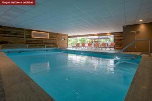 a large swimming pool with blue water in a building at Alpensonne Apartments in Bad Wiessee