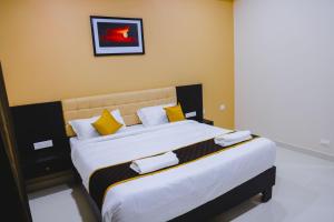 a bedroom with a large bed with yellow and white pillows at Hotel RAAGA INN in Tirupati