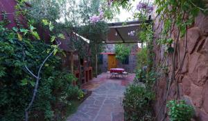 a patio with a table and a bench in a garden at laurier Rose Hostel in Ourika