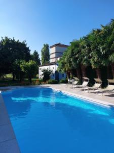 a swimming pool with chairs and a building in the background at Agriturismo Corte Spino in Nogarole Rocca