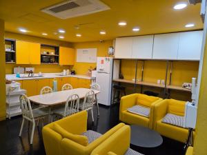 a kitchen with yellow cabinets and a table and chairs at Seri Inn Guesthouse in Busan