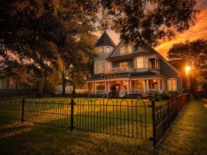a large house with a fence in front of it at Four Winds Victorian Venue & Suites in Bonham