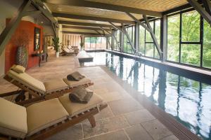 a swimming pool with lounge chairs in a building at Hôtel-Spa Le Saint Cirq in Tour-de-Faure