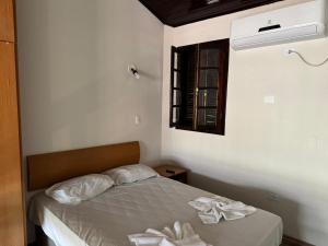 a bedroom with a bed with white sheets and a window at Hotel da Ilha in Ilhabela