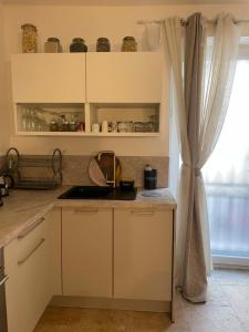 a kitchen with white cabinets and a window at Giovanna in Marseillan +3 photos