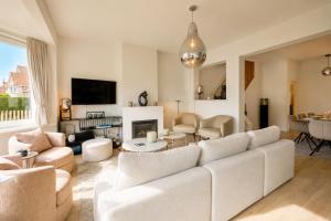 a living room with a white couch and a fireplace at Villa Duinbergen - Séjour Familial à Knokke-Heist in Knokke-Heist