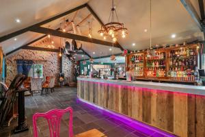 a bar with a wooden counter and pink chairs at The Hideaway - Tranquil Glamping Pod in Narberth