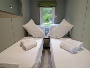 two beds in a room with white sheets and pillows at The Pines 2 Bedrooms in Northwich