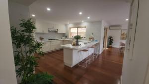 a kitchen with white cabinets and a kitchen island with bar stools at Seffa 5 vella property in Springvale South