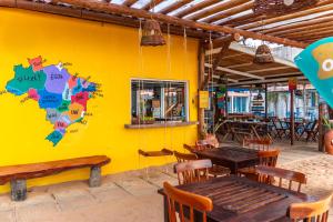a yellow wall with wooden tables and benches in a restaurant at Pousada La Bella Luna in Porto De Galinhas