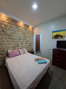 a bedroom with a large bed and a stone wall at Casa Scalesia Apartments Galápagos in Puerto Baquerizo Moreno