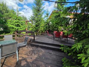 a wooden deck with chairs and tables in a garden at Pensiune Excelenta in Vermeşti