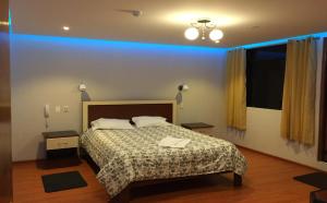 een slaapkamer met een bed en een blauw licht bij Casa Suite in Juliaca