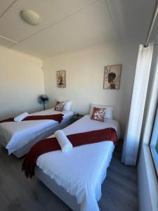 two beds in a room with white walls at Sunrise Villa Self Catering and Accommodation in Lüderitz